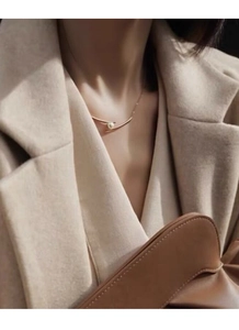 Elegant gold S925 silver necklace with single pearl shown on model in refined outfit