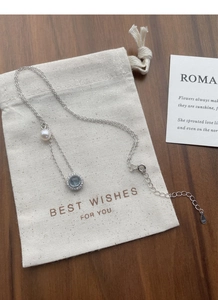 Detail view of S925 silver necklace with aquamarine gemstone and pearl on a gift pouch