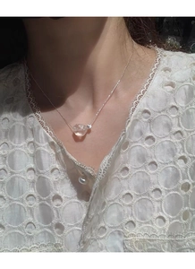 Detail view of crystal pendant and silver bead chain worn on a lace blouse