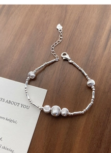 Detail of S925 sterling silver beaded bracelet with heart tag and lobster clasp on wood