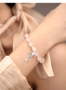Nahaufnahme des S925 Silber-Schleifenanhängers am Rosenquarz-Perlenarmband am Handgelenk