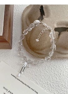 Detailansicht eines klaren Kristallperlenarmbands mit silbernem Schleifenanhänger