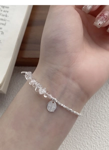 Detail of S925 silver bracelet with clear crystals and Good Luck engraved round charm