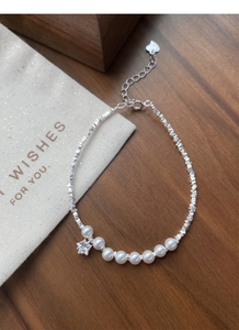 Macro shot of S925 silver bracelet featuring pearls and star crystal on wooden desk
