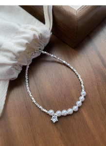 Macro shot of silver crushed beads, elegant white pearls and a sparkling star charm