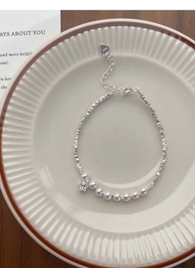 Detail of S925 sterling silver bracelet with white pearls and a star-shaped zircon pendant