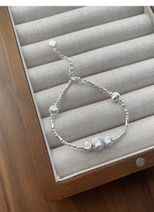 Detailed close-up of S925 silver beaded bracelet with heart tag in a wooden jewelry box