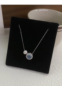 Detail of S925 silver necklace with blue gemstone and white pearl on black display