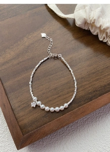 Macro detail of S925 sterling silver stamp on heart tag of a pearl and star bracelet