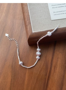 Detail view of S925 sterling silver beaded bracelet with heart charm on wood surface