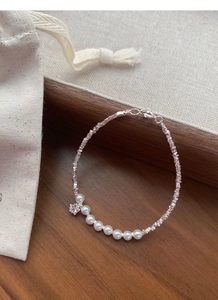 Detail of silver beaded bracelet featuring white pearls and a star-shaped crystal charm