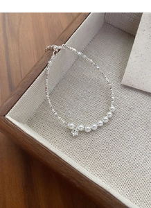 Macro detail of S925 silver bracelet featuring white pearls and a sparkling star charm pendant