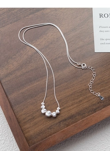Detail of S925 sterling silver snake chain with metallic beads on a wooden tray