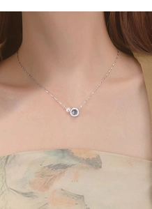 Detailed view of S925 silver necklace with freshwater pearl and blue gemstone on neck