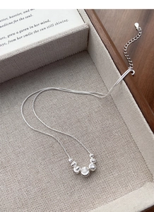 Close-up of S925 sterling silver snake chain necklace with five gradient metal beads on linen
