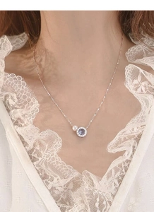Close-up of S925 silver necklace with blue gemstone and freshwater pearl pendant on model
