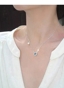 Detail of S925 silver necklace with blue aquamarine pendant and white pearl on neckline