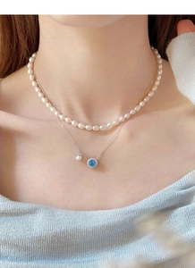 Close-up of S925 silver layered necklace with freshwater pearls and blue gemstone pendant