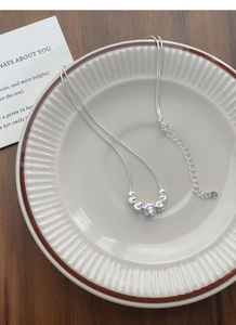 Detailed macro view of S925 sterling silver ball necklace on white ceramic plate