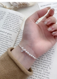 Detailed shot of a silver pearl bracelet with a sparkling star charm on a woman's wrist