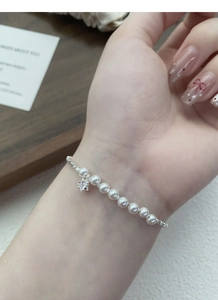 Detailed macro view of S925 silver pearl bracelet with a sparkling star charm on wrist