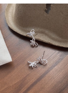 Detailed macro view of S925 sterling silver double bow earrings with hallmark on wooden surface