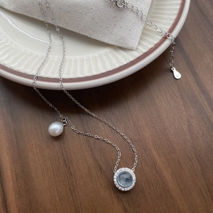 Elegant S925 silver necklace featuring teardrop pearl and blue gemstone on ceramic tray