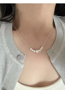 Close-up of S925 sterling silver necklace featuring seven gradient metal beads on clavicle