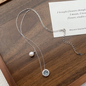 S925 silver necklace with freshwater pearl and round aquamarine pendant on walnut tray