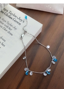 Detail of adjustable silver chain bracelet with blue and clear teardrop zircon stones
