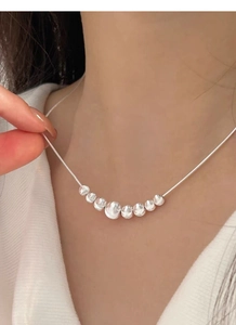 Detail of silver S925 necklace with gradient beads and fine snake chain on a model