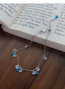 Detail of adjustable silver bracelet with blue and clear zircons on a vintage book