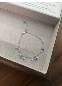 Detailed shot of silver bracelet with blue zircon teardrop charms and adjustable slider