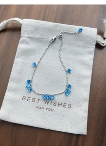 Macro detail of silver bead chain bracelet featuring blue teardrop crystal and sliding clasp