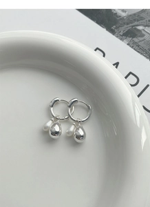 Detail of 925 silver hoop earrings with polished metal drops and white baroque pearls