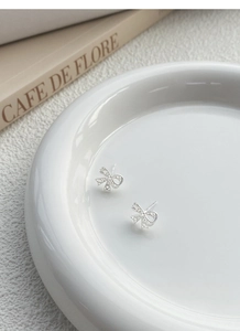 Vista macro degli orecchini a fiocco in argento S925 con design a filigrana cava delicata