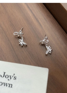 Close-up of S925 sterling silver double bow earrings on a rustic wooden background