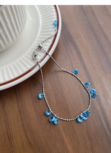 Detailed macro view of 925 silver beaded bracelet with teardrop blue zircons on wood