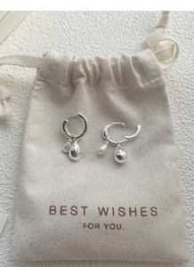Macro detail of 925 sterling silver hoop earrings with teardrop and pearl pendants