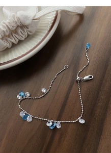 Close-up of S925 silver adjustable bracelet with blue zircons on walnut wood surface