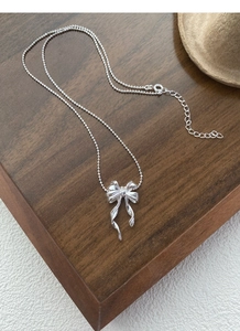 Détail du collier papillon en argent S925 sur surface texturée avec chaîne à billes