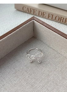 Detailed macro view of S925 sterling silver bowknot ring with drop charms and woven lines