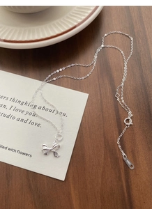 Detailansicht des S925-Prägestempels auf einer Schleifenkette aus Silber über Holzdekor
