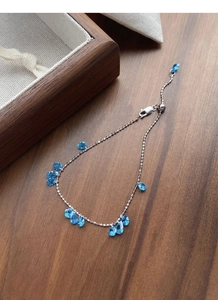 Detail of silver chain bracelet with blue teardrop zircon stones on wood background