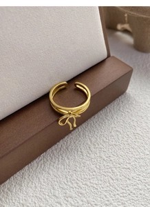 Macro shot of gold ribbon bow ring featuring a double-layered adjustable band detail