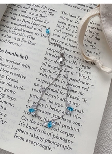 Detail of silver chain bracelet with blue teardrop zircon on an open book