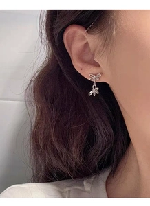 Close-up of elegant S925 sterling silver double bow earrings worn by a model