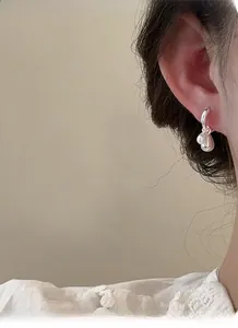 Detailed close-up of 925 silver irregular teardrop earring worn with white lace dress