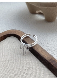 Close-up of S925 sterling silver bow ring with double band on minimalist background