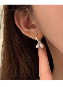 Close-up of model wearing 925 sterling silver hoop earrings with a sleek drop pearl pendant